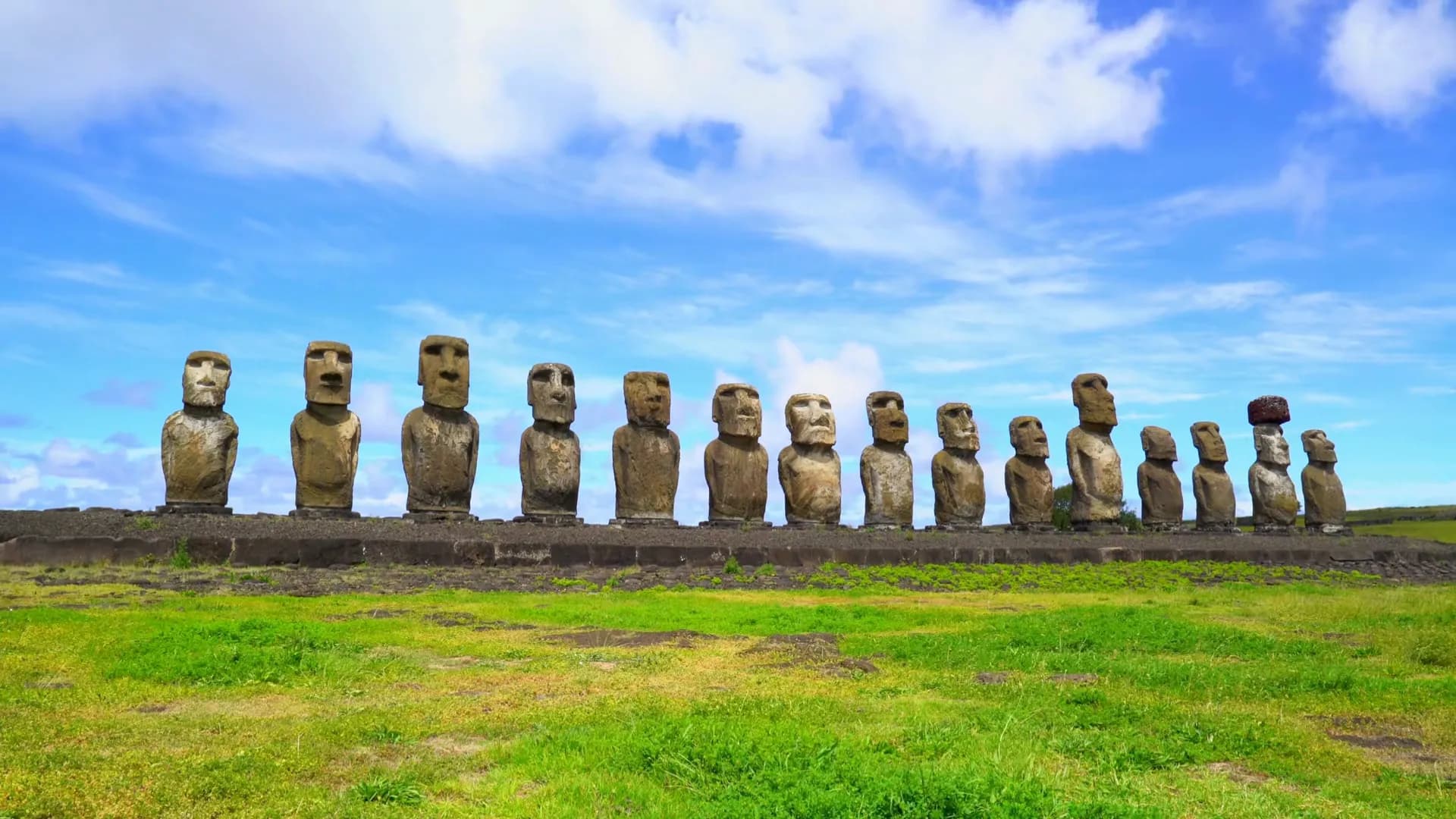 Fila de moáis sobre el pasto de la isla